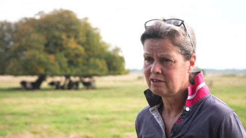 Farmer Nicola Chapman standing in a field with cows in the background