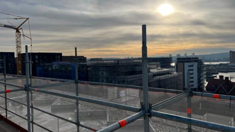 Building scaffolding overlooking another building site with Thames and sun in background