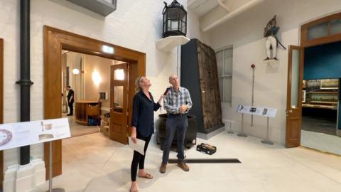 A man and a woman stand chatting inside the Hull Maritime Museum