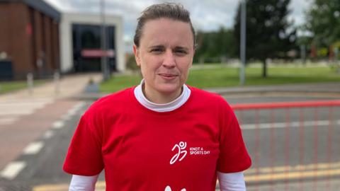 A woman in a red t-shirt over a white top. The t-shirt says Knot A Sports Day on the front