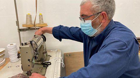 A man sits at a sewing machine