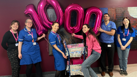 Staff from the Jessop Wing stood with the number 1,000 in pink balloons.