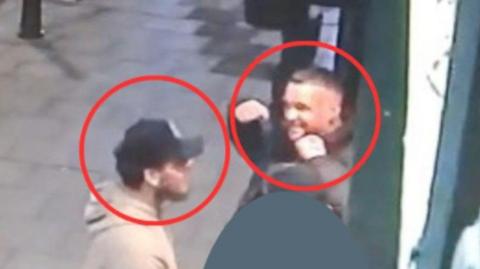 Two men are in the image and a red circle is around each head. They are standing on a pavement.