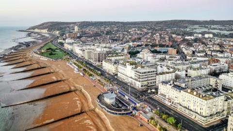 An aerial view of Eastbourne, showing large white buildings along the beach at low tide. 