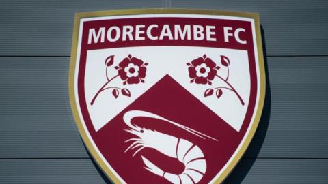 A shot of Morecambe's badge on the exterior of their Mazuma Mobile Stadium
