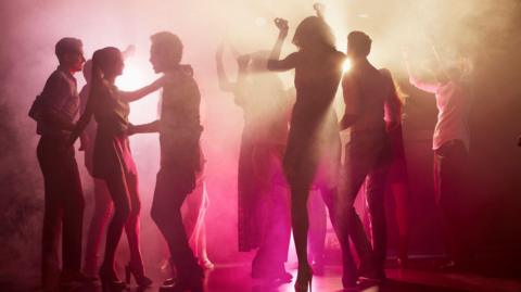 Silhouetted people dancing on a nightclub floor