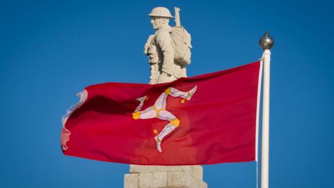 A Manx flag flying in front of the soldier on top of Douglas Promenade War Memorial