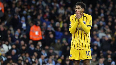 Georginio Rutter holds his face with his hands in disappointment during Brighton's game at Manchester City