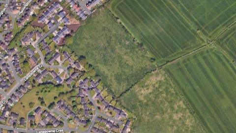 An aerial view from Google Maps of a residential area which butts up against empty farmland. The labelled streets are Lansdowne Crescent and Lansdowne Close. 
