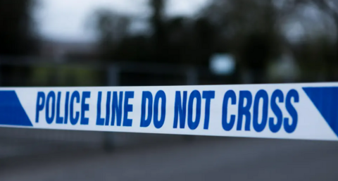 Police tape in white and blue reading "police line do not cross"
