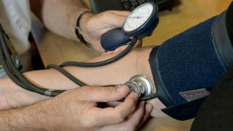 A doctor checking a patient's blood pressure in their practice room 