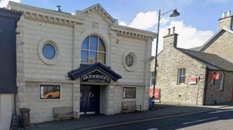 A nightclub entrance in Thurso with a light brick building and a blue archway over the door with the name Skinandi's on the top