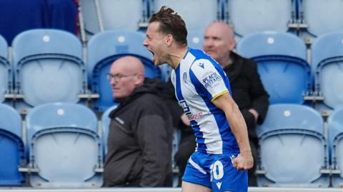 Jack Payne runs with his fist clenched and his mouth open in celebration at a goal