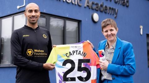 Ex-Wolves captain Karl Henry with Louisa Craig after surprising her with the award. They are standing outside the school and holding a special shirt.