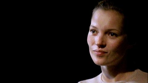 A close up of Kate Moss in front of a black background