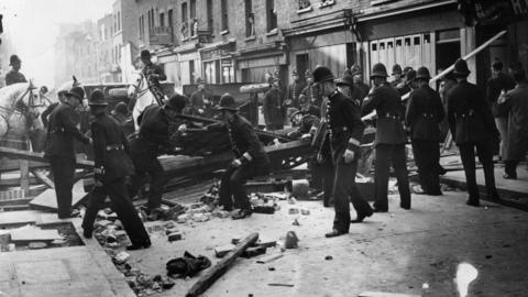 Black and white image of police fighting with anti-fascists protesters on Cable Street.