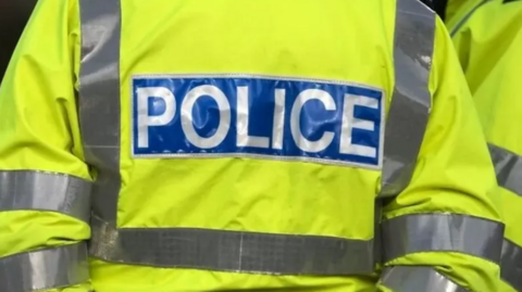 The back of a police officer wearing a hi-vis jacket.