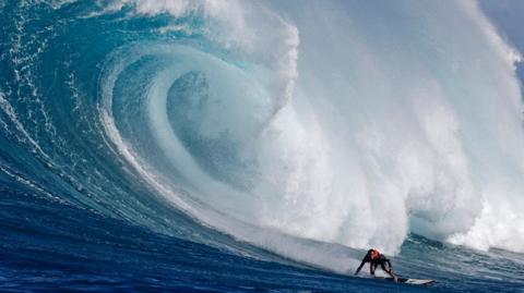 Hawaiian surfer Noah Beschen catches a wave at the Pe'ahi Jaws Surf Break on the island of Maui, Hawaii