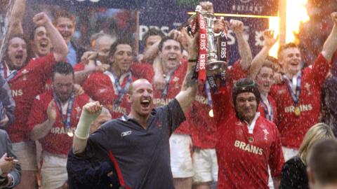 Gareth Thomas and Michael Owen hold the Six Nations trophy in front of celebrating Wales players