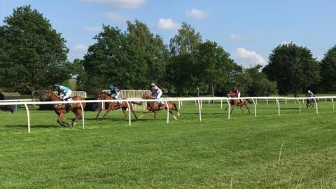 A view of a racecourse with jockeys riding horses during a race. 