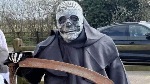 A man dressed as the Grim Reaper holding a scythe