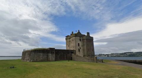 A castle set in front of a river with a grassy area in front