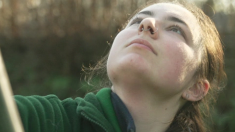 A woman looking up with a green top