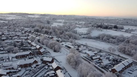 An aerial view of houses and fields covered in snow