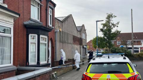 Two forensics officers enter a cordoned off property in Wharton Terrace, Hartlepool, after a man was attacked in the street