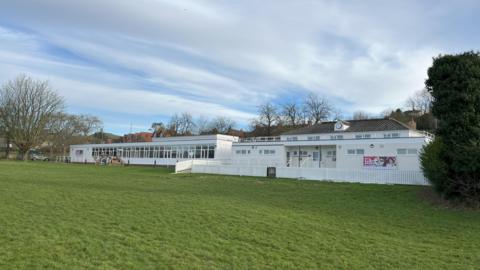 The picture shows the outside of Tor Sports and Leisure facility. The building is white in colour and there is grass in the foreground. 