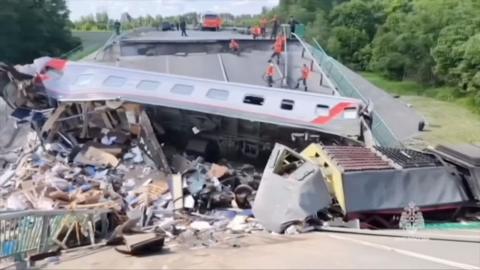 A derailed passenger carriage is seen surrounded by debris on the collapsed bridge