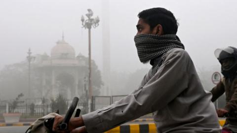 man on a bike surrounded by smog. 