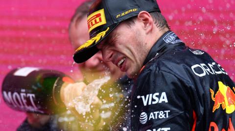 A Red Bull team member sprays champagne on Max Verstappen after the Dutchman won the Azerbaijan Grand Prix