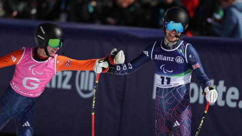 James Hannan and Fred Warburton bump fists after crossing the finish line of the downhill at the Winter Paralympics