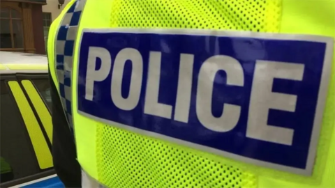 The back of a police officer, who is wearing a hi-vis jacket.