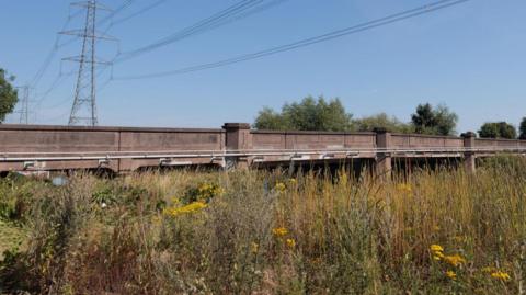 Zouch Bridge with a pylon, trees and foliage nearby