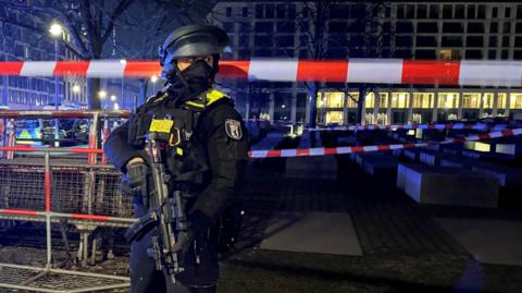 A policeman stands in front of a police cordon. 