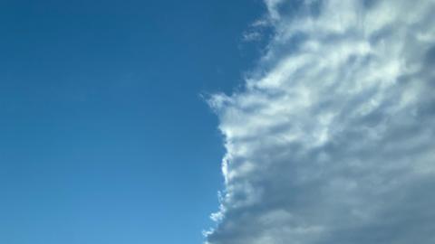 The cloudy edge of a weather front moves across a blue sky   