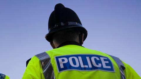 A generic image showing the back of a police officer. He is wearing a helmet.