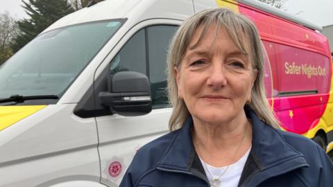 A woman stands in front of a brightly painted band