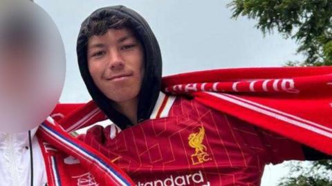 Mason Osborne posing for a photo wearing a Liverpool football shirt and scarf