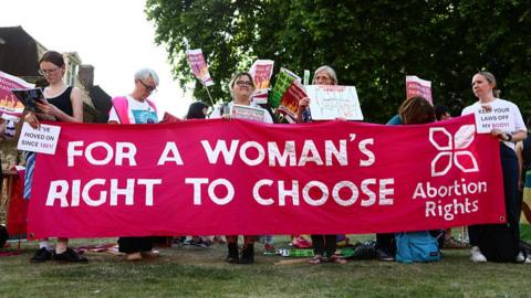 Female protestors hold up a banner which reads "For a women's right to choose".