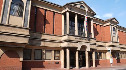 Image of Leicester Magistrates’ Court, which is a red brick building with a Union flag flying outside.