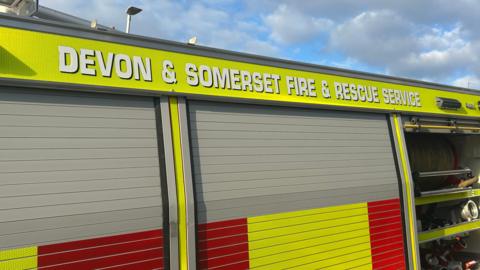 A picture of the side of a Devon and Somerset fire vehicle. It is red and green in colour with the force name at the top of the vehicle.