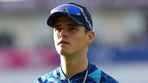 Jacob Bethell in a baseball hat, with sunglasses on the brim