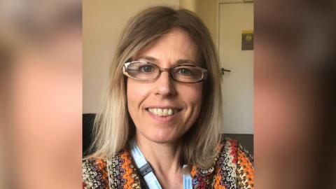 A woman with blonde hair and glasses smiling at the camera