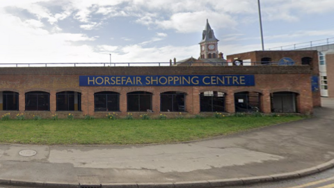 A brown brick car park with a sign reading "Horse Fair Shopping Centre"