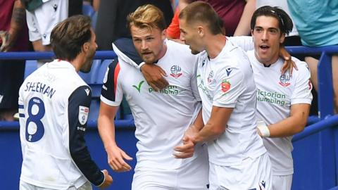 Bolton players, wearing their white home shirt, celebrate a goal against Preston