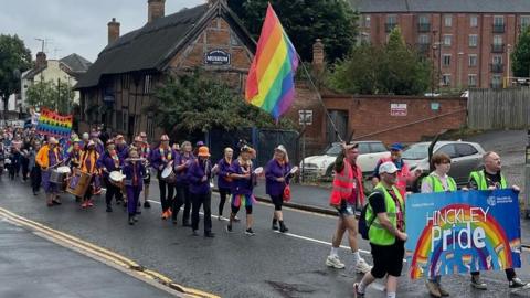 A view of the Hinckley Pride parade in 2024, with a giant rainbow flag flying in the air.