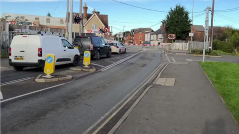 Two cars and a van queue at the London Road level crossing in Bicester. 